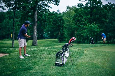 A golfer chips the ball near the green.