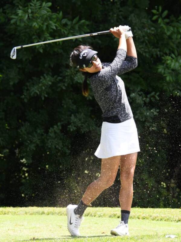 A female golfer hits a pitch shot.