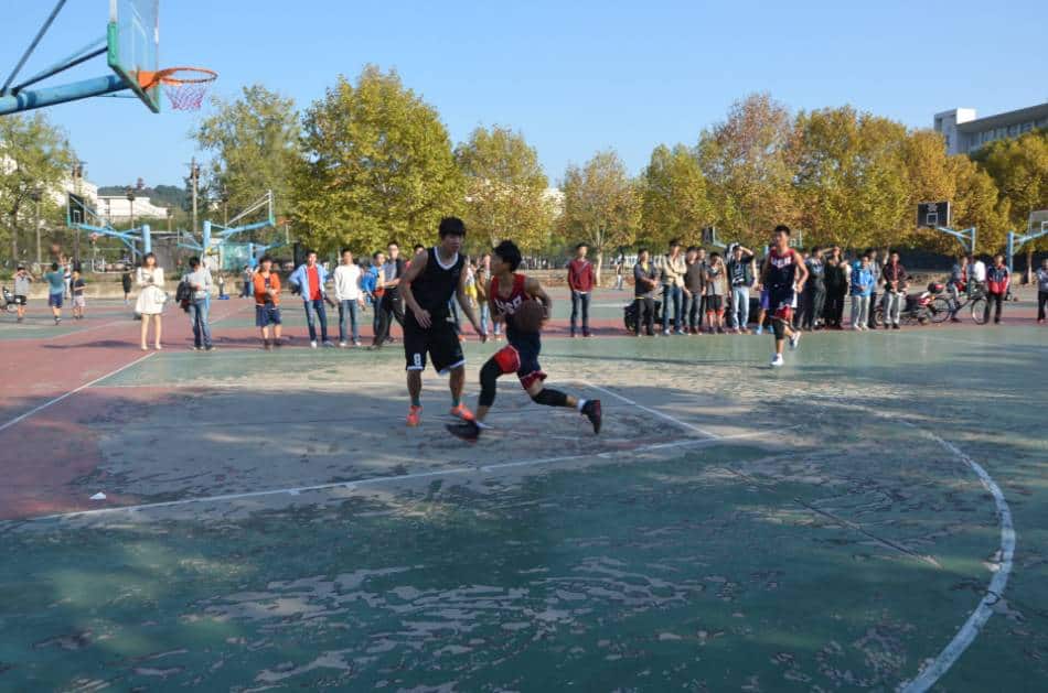 A basketball player drives toward the rim on an outdoor court.