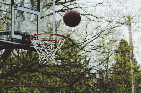 The basketball about to go into the net.