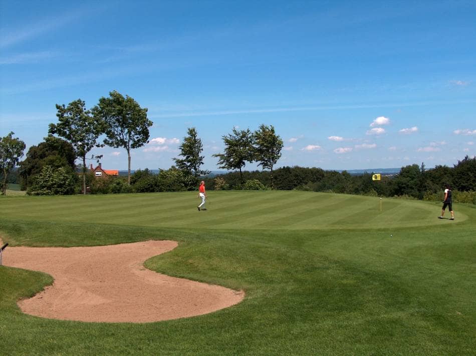 Two golfers on the green of a hole.