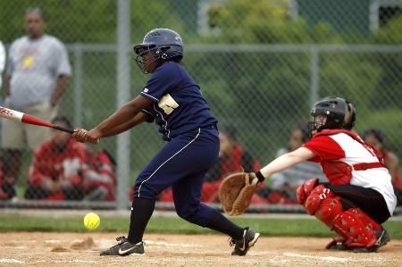 A youth softball player makes contact with the ball.