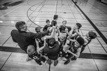 A youth basketball team huddles up before a game.