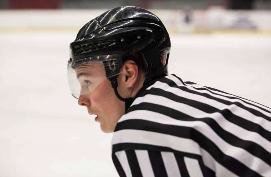 A hockey ref looks on at the game.