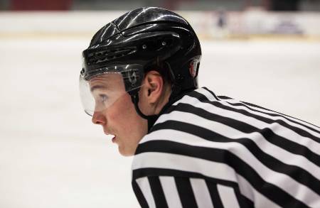 A hockey ref looks on at the game.