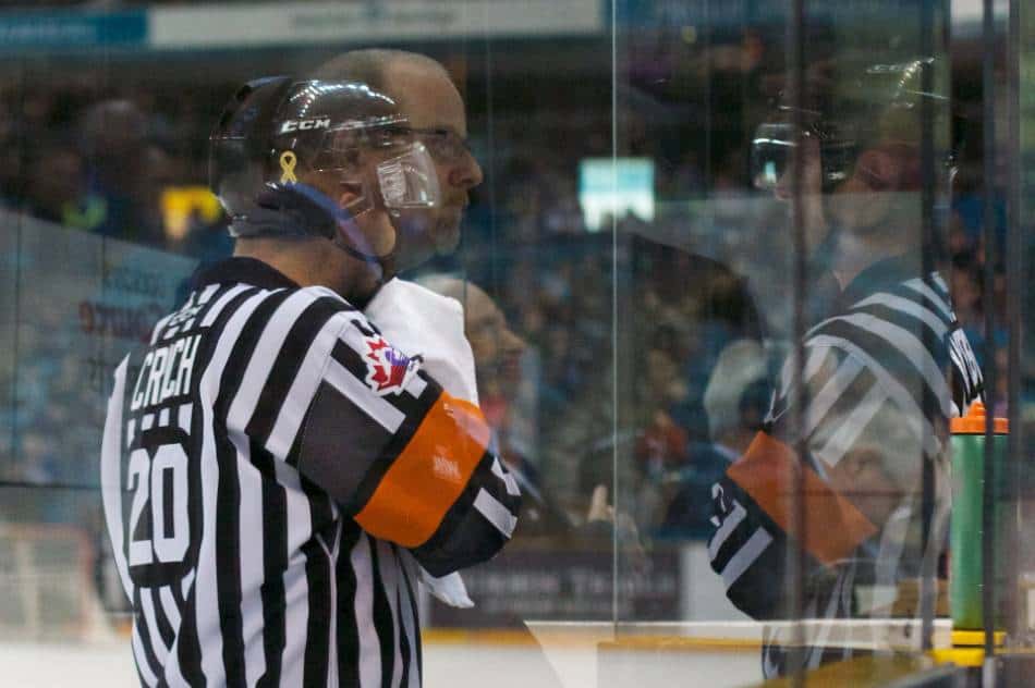 A hockey ref wipes down his face during a timeout.