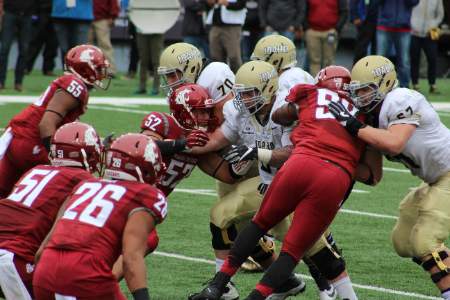 College football players rushing Idaho's quarterback.