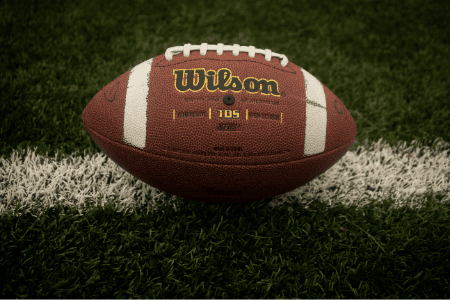 A Wilson football lying on a football field.