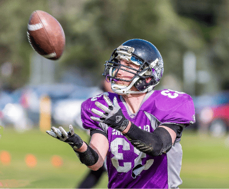 A wide receiver places his hands out to catch the ball.