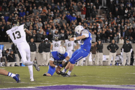 A college football kicker strikes the ball during a field goal.