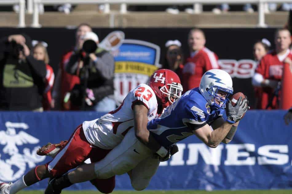 A college football wide receiver makes a diving catch.