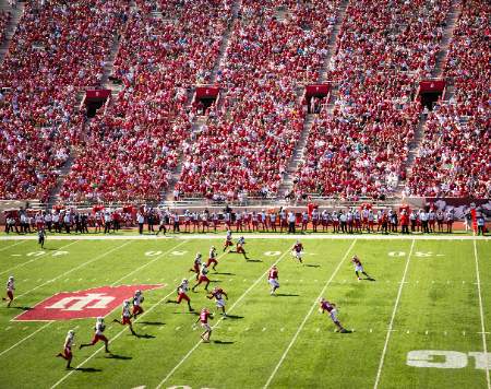 College football players sprint downfield after a kickoff.