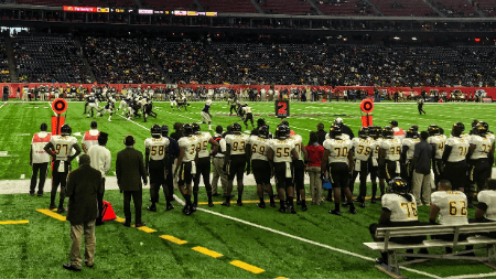 Football players standing on the sideline.