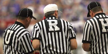 NFL referees huddle to discuss a play.